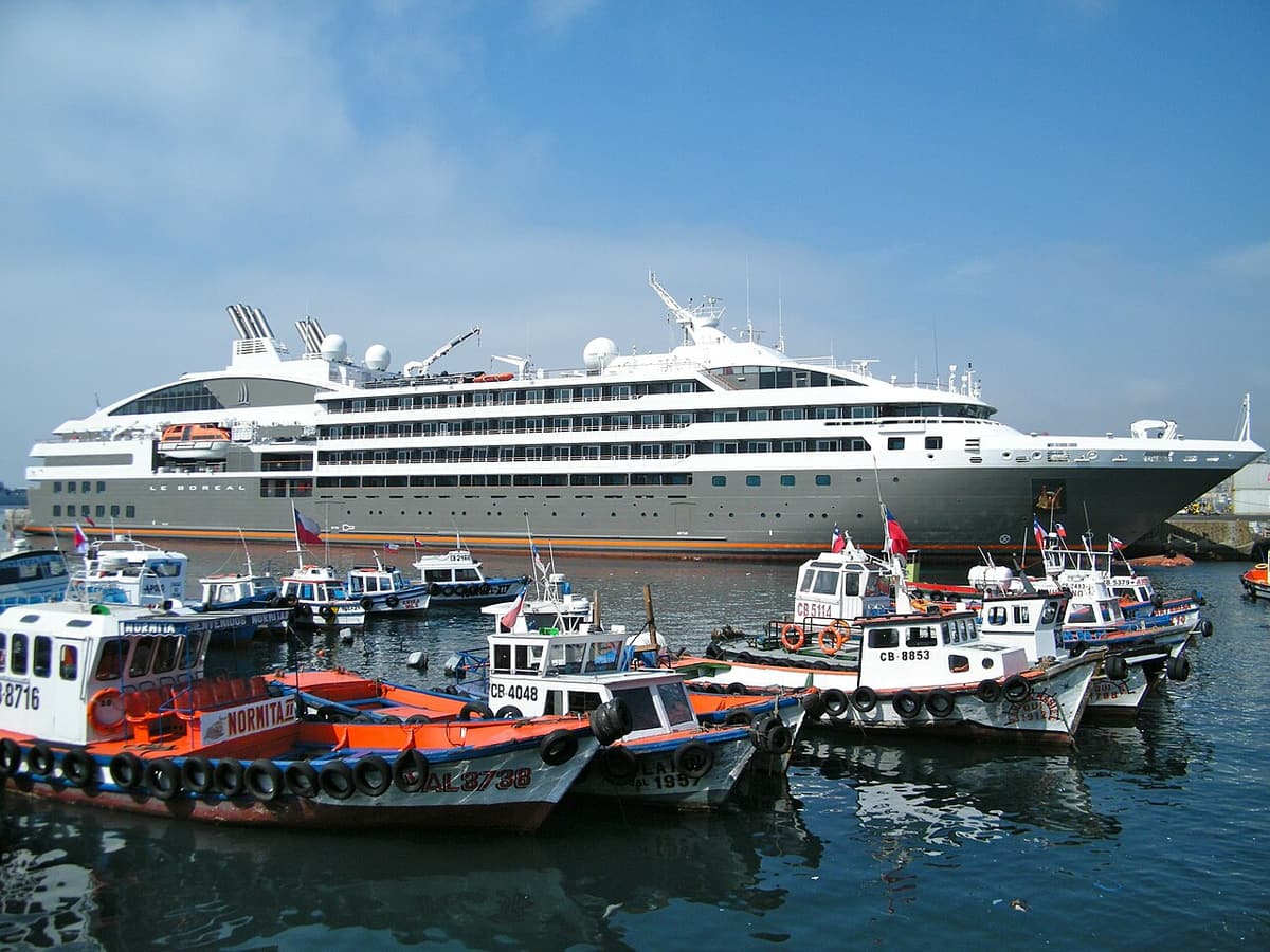 A white cruise ship moored behind fishing boats in the port of Valparaíso